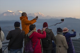 Asian-looking tourists watching and photographing sunrise as well as shooting selfies on the second