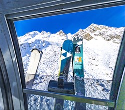 View through a gondola window of the Schwarze Schneid cable car onto skis and snow-covered
