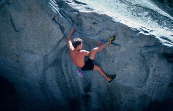 Young man with climbing shoes, chalk bag, bouldering in Yosemite Valley, California, USA,