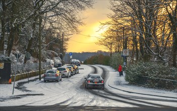 Cars driving carefully on a snow-covered road at dusk, Wuppertal Vohwinkel, North Rhine-Westphalia,