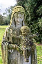 Green lichen growing on stone memorial statue of Mary and baby Jesus, Eddington, Hungerford,