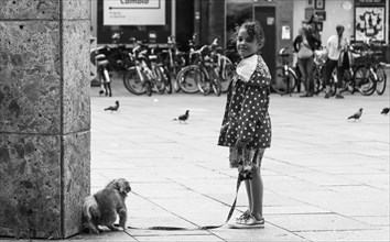 A little girl holds the leash of a dog on a city street, Hohenzollernbruecke, Cologne Deutz, North