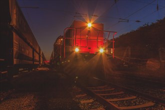 Locomotive illuminates the tracks at night with headlights, Lower Rhine, North Rhine-Westphalia,