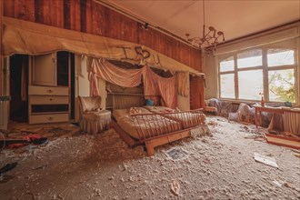 An abandoned and devastated bedroom with overturned furniture and graffiti on the wall, urologist's