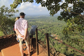 Two people looking down at the water gardens from rock palace fort, Sigiriya, Central Province, Sri