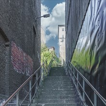 Urban scene with a staircase between two buildings and graffiti wall, Wuppertal Elberfeld, North