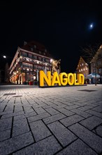 Moon over the square with half-timbered houses and 'NAGOLD' lettering at night, Nagold, Black