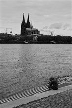 View over the Rhine with cathedral and lone person in front of it, black and white, Cologne,