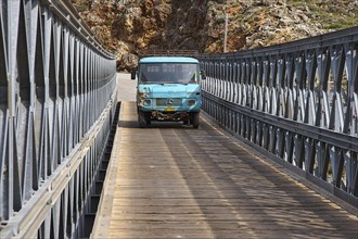 A blue lorry drives over a bridge in mountainous surroundings, Aradena Gorge, Aradena, Sfakia,