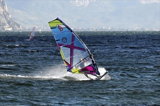 Windsurfers surfing in strong winds on Lake Garda near Malcesine, Veneto, Italy, Europe