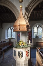 Baptismal font with heraldic shield inside church of Saint Leonard, Horringer, Suffolk, England, UK