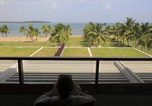Woman relaxing on hotel balcony, Amaya Beach Resort hotel, Pasikudah bay, Eastern Province, Sri