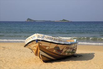 Boat on tropical beach at Nilavelli, Trincomalee, Sri Lanka, Asia with Pigeon Island in background,