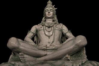 Statue of meditating Hindu god Shiva, sitting on the Ganges riverbank at the Parmarth Niketanin