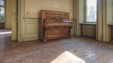 An old piano in a room with a wooden floor and large windows through which sunlight falls, Villa