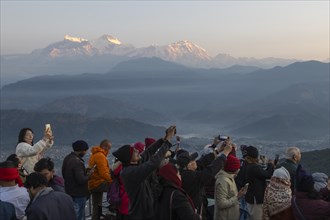 Asian-looking tourists watching and photographing sunrise as well as shooting selfies on the second