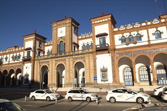 White taxi cars outside historic railway station building, Jerez de la Frontera, Spain, Europe