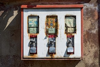 Old rusty triple chewing gum machine on a wall, vending machine for children for chewing gum and
