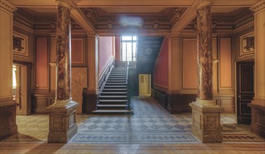 Magnificent entrance area with marble columns and a grand staircase in warm light, Villa Woodstock,