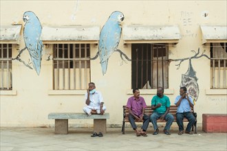 Group of men on benches, graffiti-painted wall, Pondicherry or Puducherry, Tamil Nadu, India, Asia