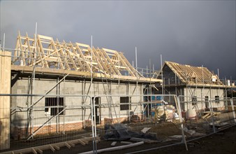 New houses under construction in the village of Bawdsey, Suffolk, England, UK dark storm clouds