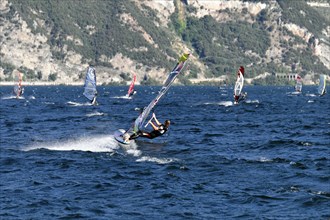 Windsurfers surfing in strong winds on Lake Garda near Malcesine, Veneto, Italy, Europe