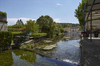 Small canal with weir and mill wheel in Goudargues, Departement Gard, Occitanie region, France,
