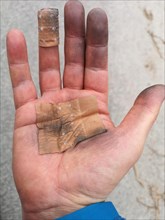 Close up of a dirty hand of a man, with protection plasters of a industry worker after finishing
