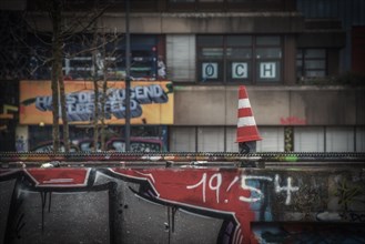 Street cone in the foreground with blurred graffiti in the background, Wuppertal Elberfeld, North