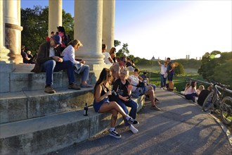 People enjoying the autumn sun at the Monopteros in the English Garden, with a view of the Munich