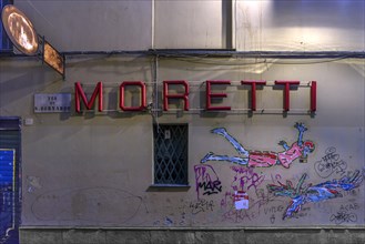 Moretti, lettering of a bar, underneath graffiti on a house wall, historic centre, Genoa, Italy,
