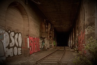 Abandoned tunnel with tracks and colourful graffiti on the walls, former Rethel railway branch,