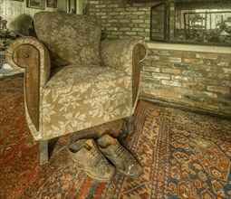 An armchair and a pair of old shoes in a room with a brick wall, Maison Limmi, Lost Place, Kalken,