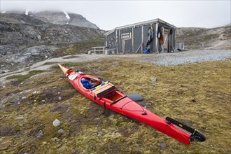 Sea kayaker using Texas Bar as shelter, old fur trapper cabin at Worsleyhamna, Liefdefjorden,