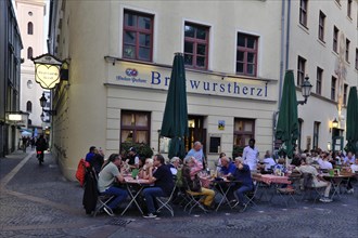 People sitting in the garden in front of the traditional restaurant Bratwurstherzl at