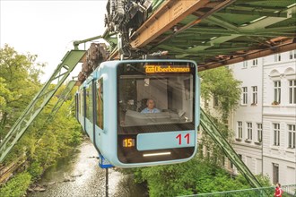 A suspension railway crosses an urban scenery near a suspension bridge, suspension railway,
