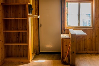 Sun shining through window into abandoned rustic cabin with built-in bookcase and kitchen bar