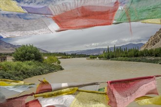 Mid-summer view of the Indus River, seen from the Buddhist prayer flags decorated bridge in Central