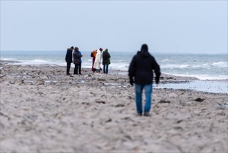 A group of people watching something on the beach in cold weather, Baltic Sea,
