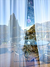 Christmas Tree with Window Reflection and View over a Terrace and Tree and Mountain in Lugano,