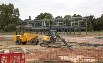 Steel frame of new building at construction site with machinery, Melton, Suffolk, England, UK