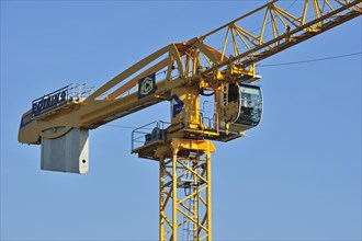 Yellow construction crane on building site showing cabin and counterweight, France, Europe