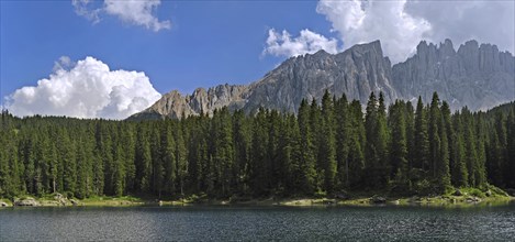 The lake Lago di Carezza, Karersee surrounded bij mountain peaks and pine forest in the Dolomites,