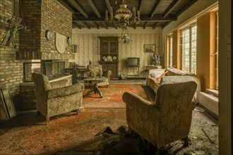Abandoned-looking living room with worn furniture and caved-in floor, Maison Limmi, Lost Place,