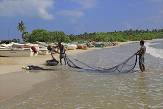 Men with fishing nets on tropical beach at Pasikudah Bay, Eastern Province, Sri Lanka, Asia