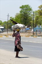 African woman carrying scrap metal on her head through the streets, street scene, Kongola in