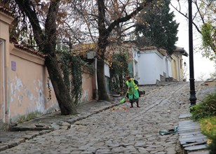 Woman sweeping cobbled street in old town of Plovdiv, Bulgaria, eastern Europe, Europe