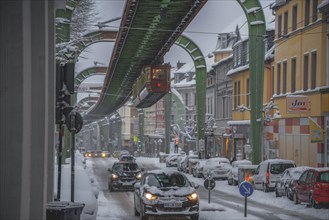 Snow-covered city street with moving cars under an overhanging railway line, wintry atmosphere, The