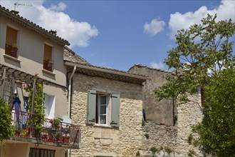 Old sandstone-walled houses with windows, shutters, balcony and a balcony in Goudargues, Gard