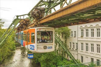 Suspension railway crossing a bridge in the city, river and buildings in the background, suspension